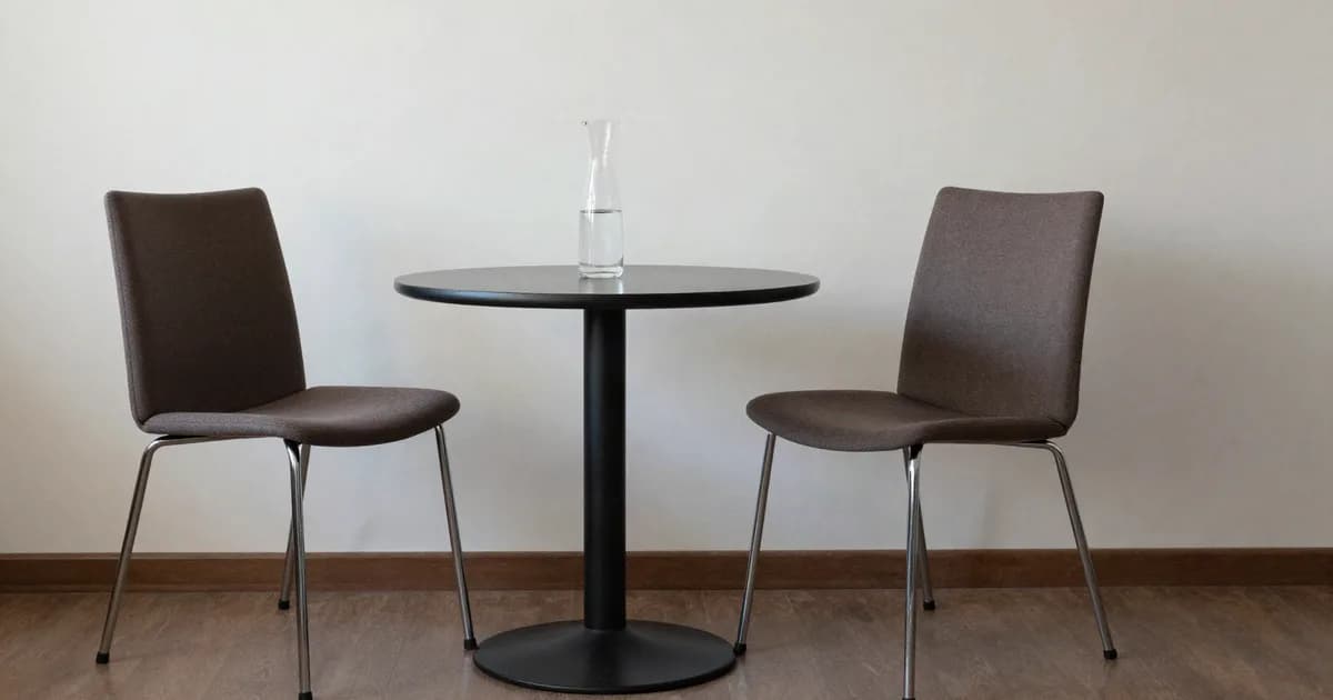 Two chairs facing each other around a round table in a neutral room