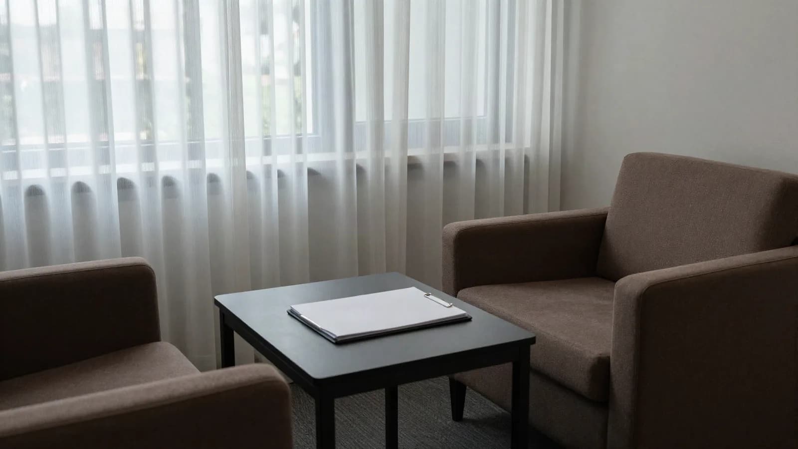 Salon de réunion privé à deux fauteuils et un dossier unique sur la table basse — investissement discret d'un family office