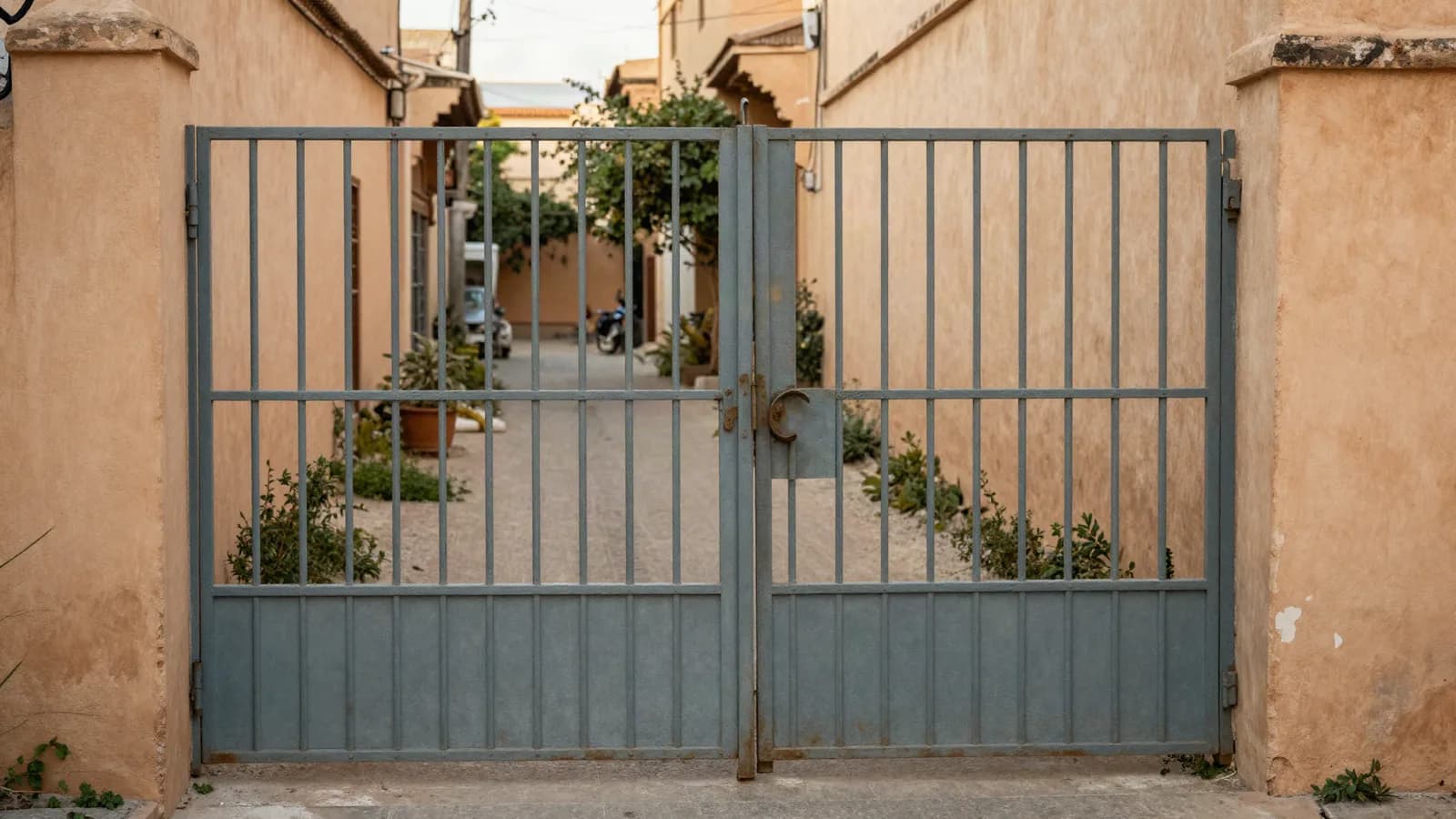 Portail métallique fermé devant une maison marocaine, allée envahie derrière — récupérer un bien occupé à distance